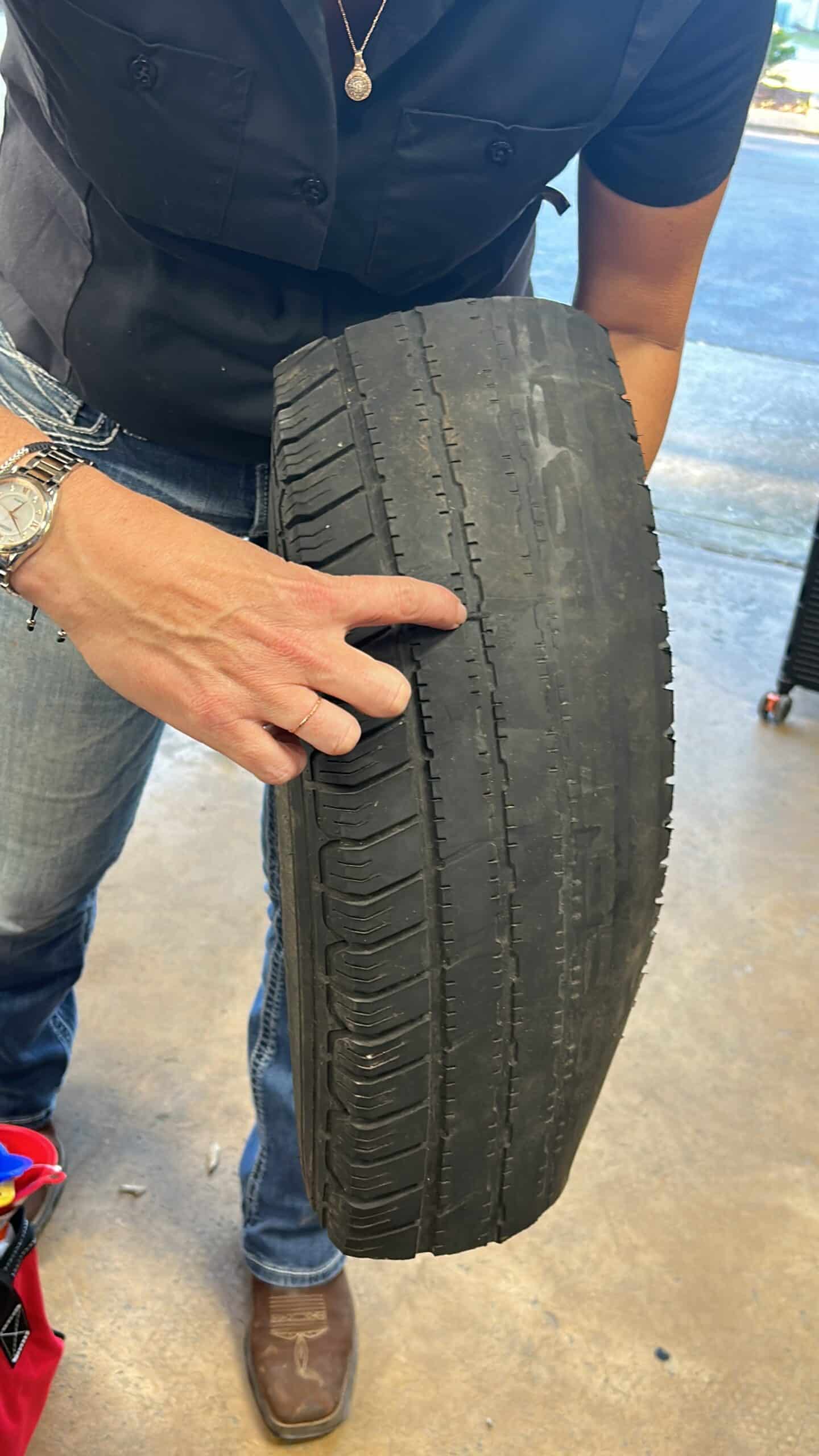 technician points to a tire showing the stages of wear and tear on the treads of a tire