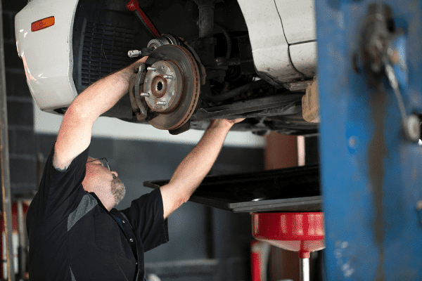 Alignment - Man fixing axels on a car. The brakes are also visible.