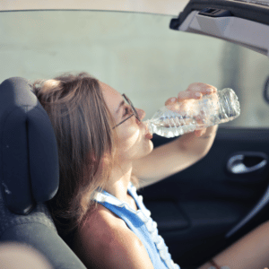 A malfunctioning car heating and air system. Picture of a woman in a convertible drinking a bottle of water. This is for the article, "How Your Vehicle Is Like the Human Body."