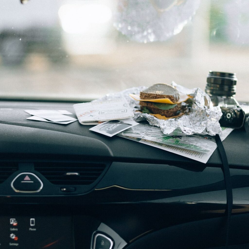 Picture of a half-eaten sandwich in aluminum foil wrapper on the dash of a car.