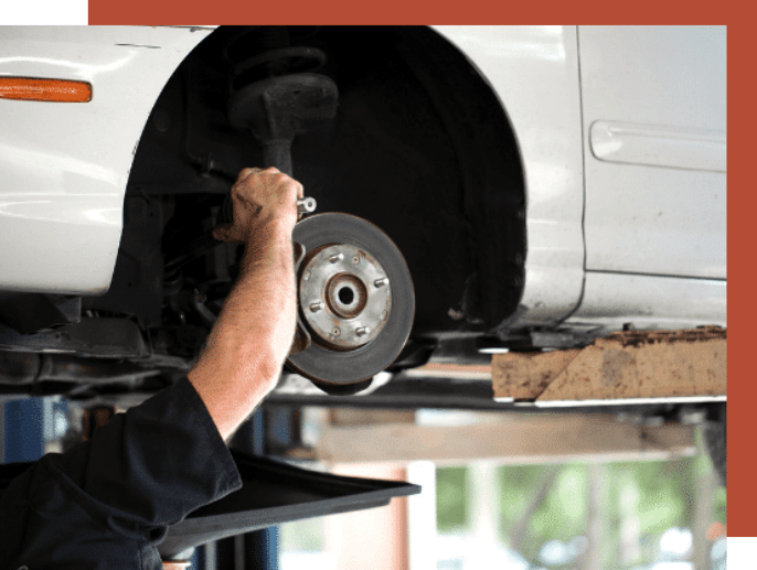 Man working on a vehicle wheel axel as part of City Auto's Steering and Alignment Services.