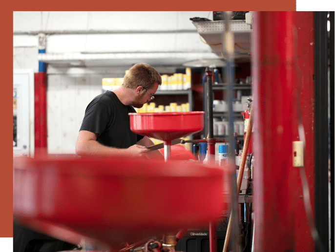 auto technician preparing to perform gas fuel services with various funnels and equipment 